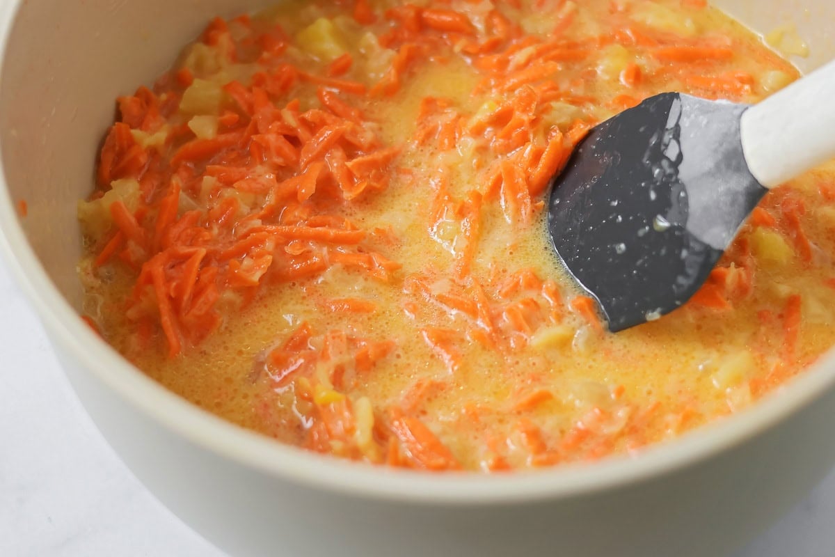 Adding carrot to wet mixture in a bowl.