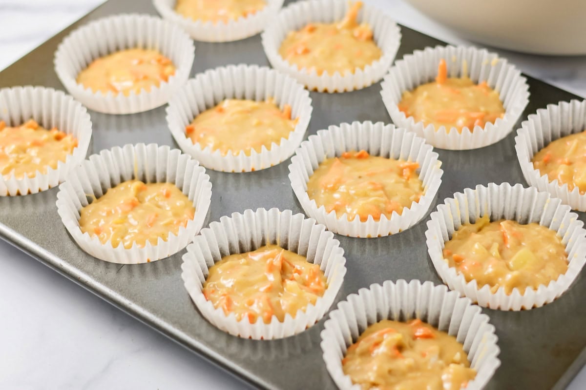 Batter in muffin liners in a pan.