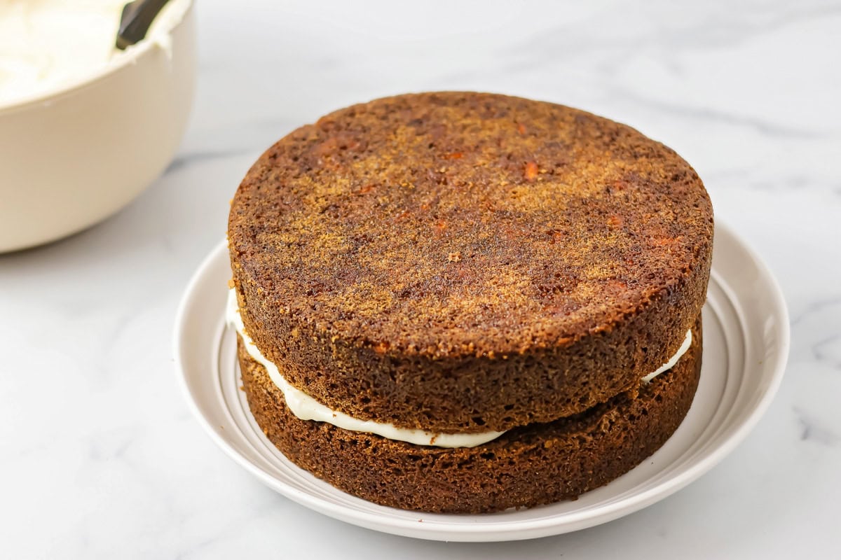 Two baked cake rounds stacked with frosting in the center.