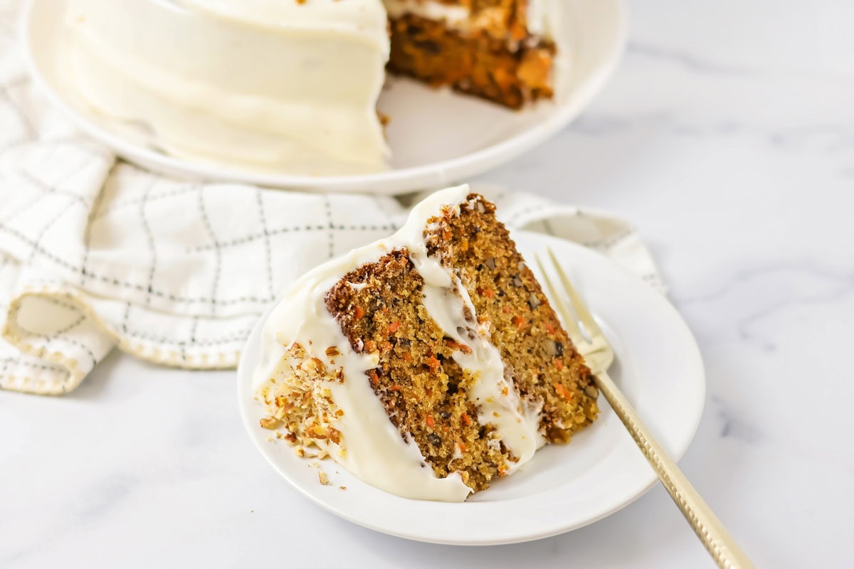 A slice of homemade carrot cake on a white plate.