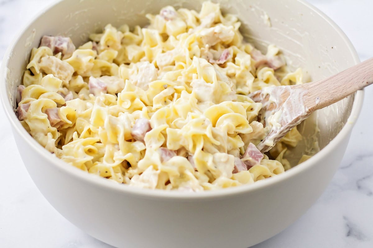 Adding pasta to cubed cheese and ham.