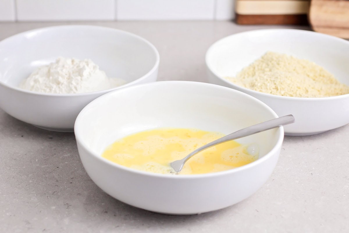 Ingredients for dipping chicken tenders in white bowls.