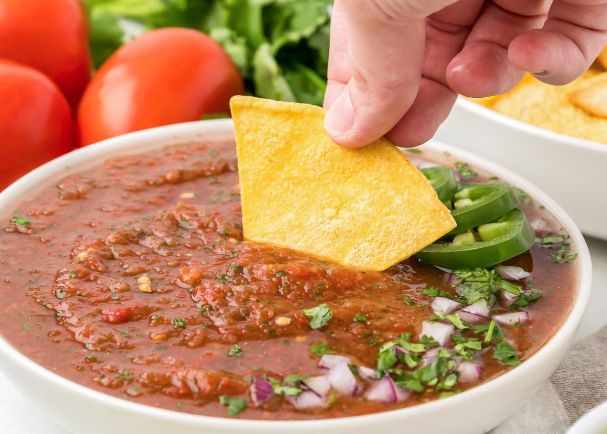 Dipping a tortilla chip in a bowl of homemade Chili's salsa.