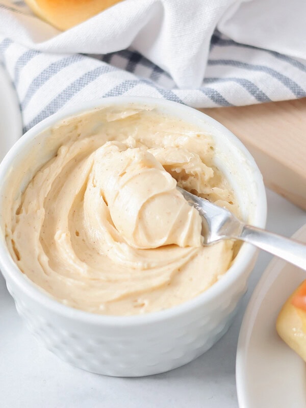 Cinnamon butter in small, white bowl with butter on knife.