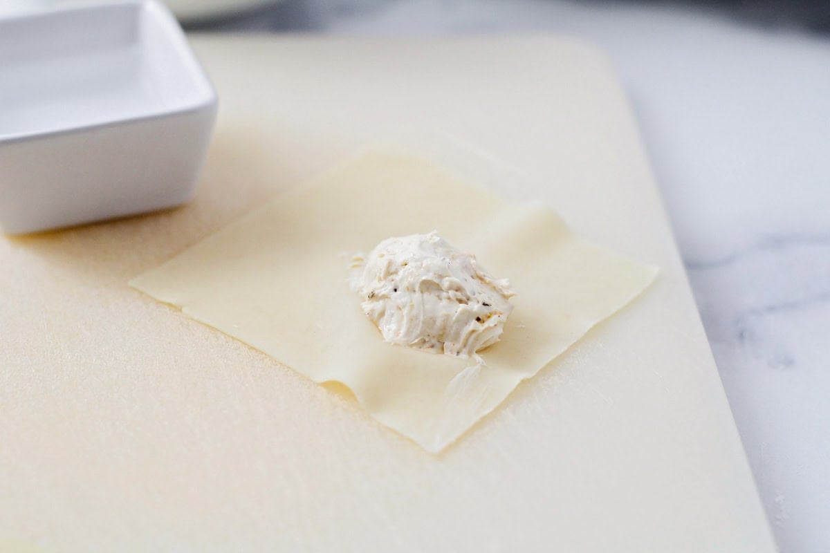 Adding cream cheese filling to the wrappers.