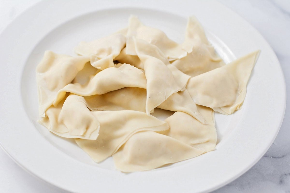 A plate of filled wontons ready to be fried.