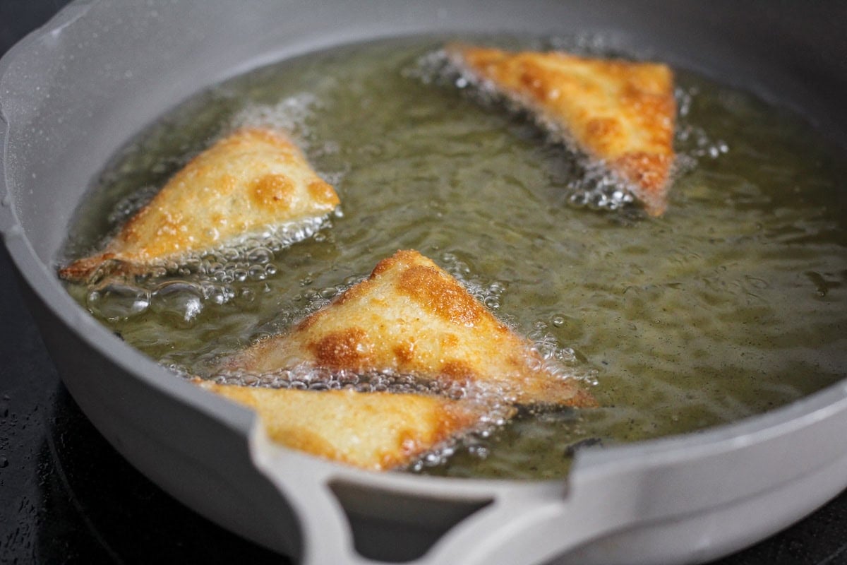 Wontons frying in a pan of oil.