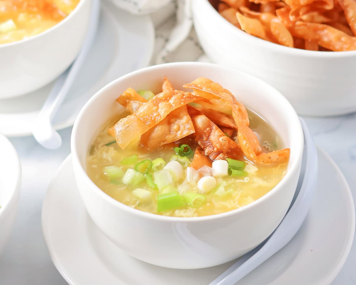 Homemade egg drop soup in a small soup bowl topped with crispy wonton strips.