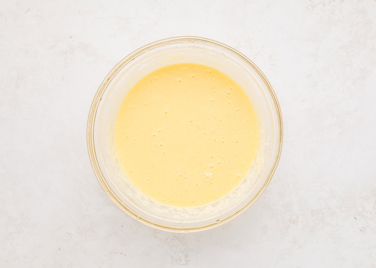 Wet ingredients for eggnog bread mixed together in glass bowl.