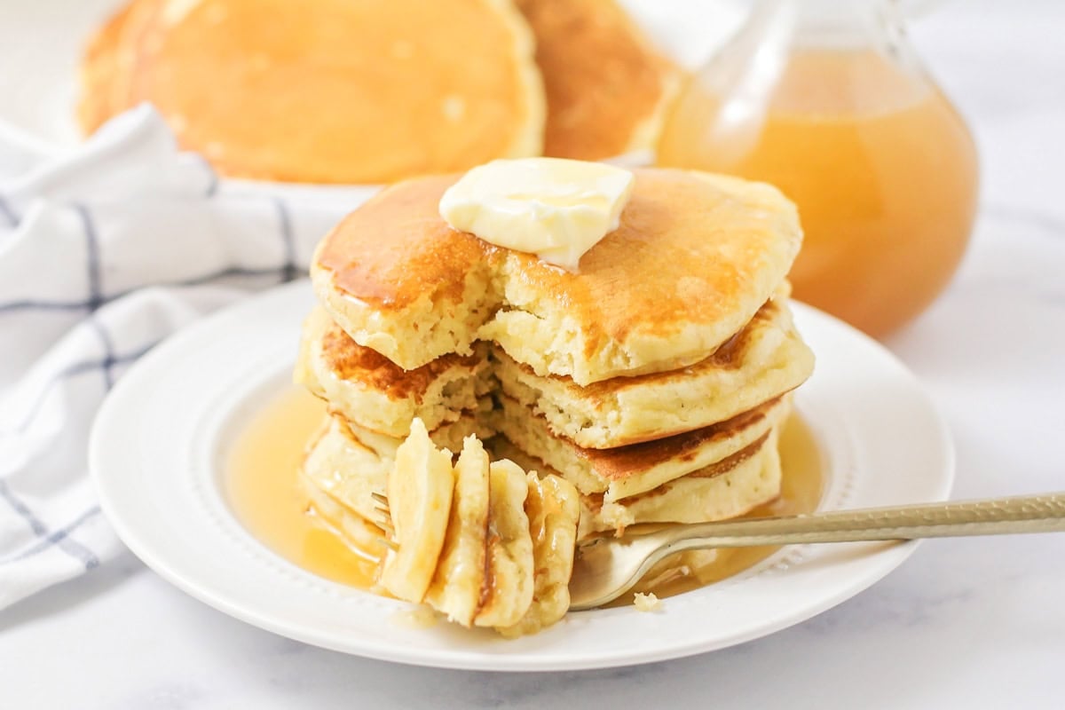 A stack of fluffy pancakes with a bite missing.