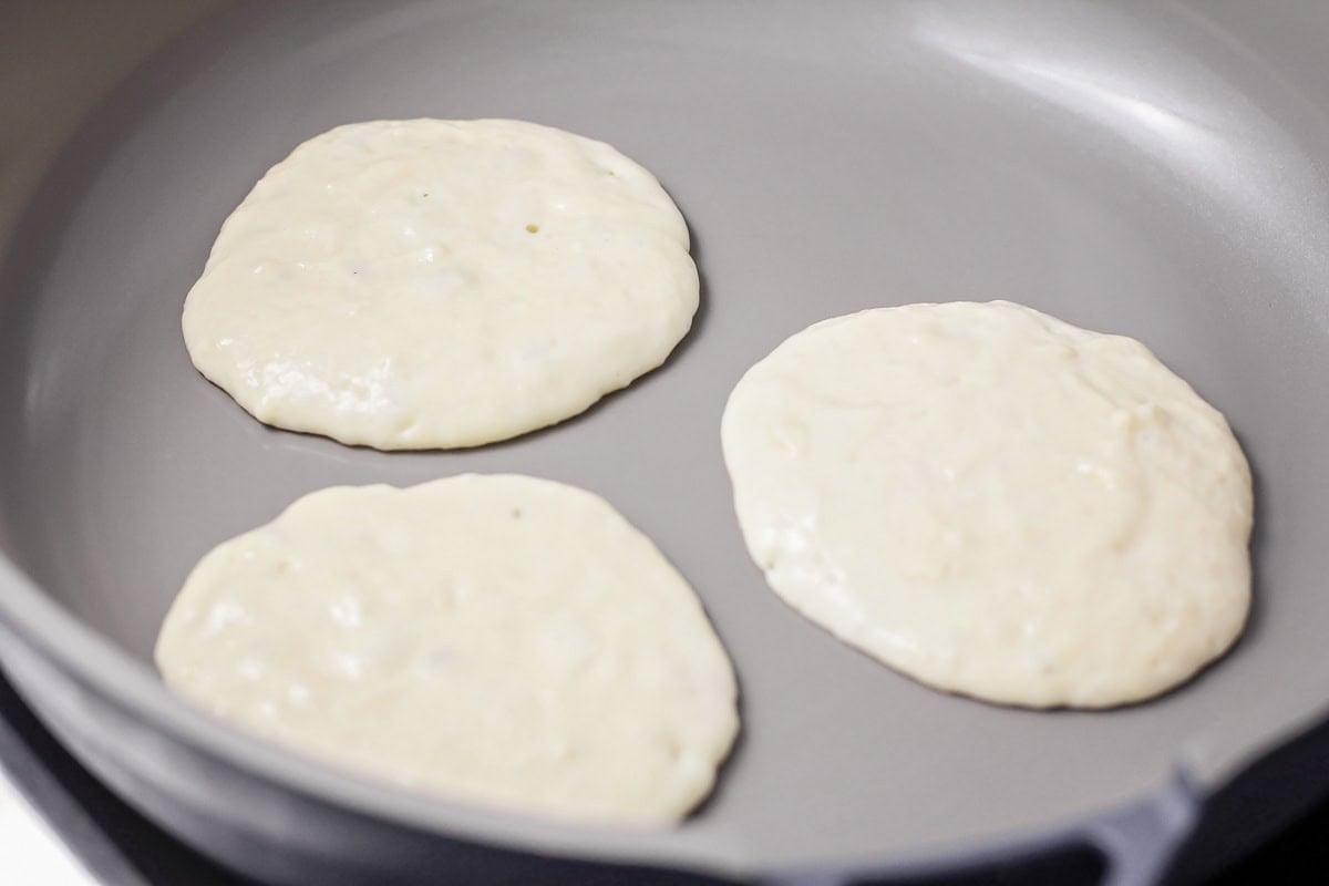 Pancakes cooking in a skillet.