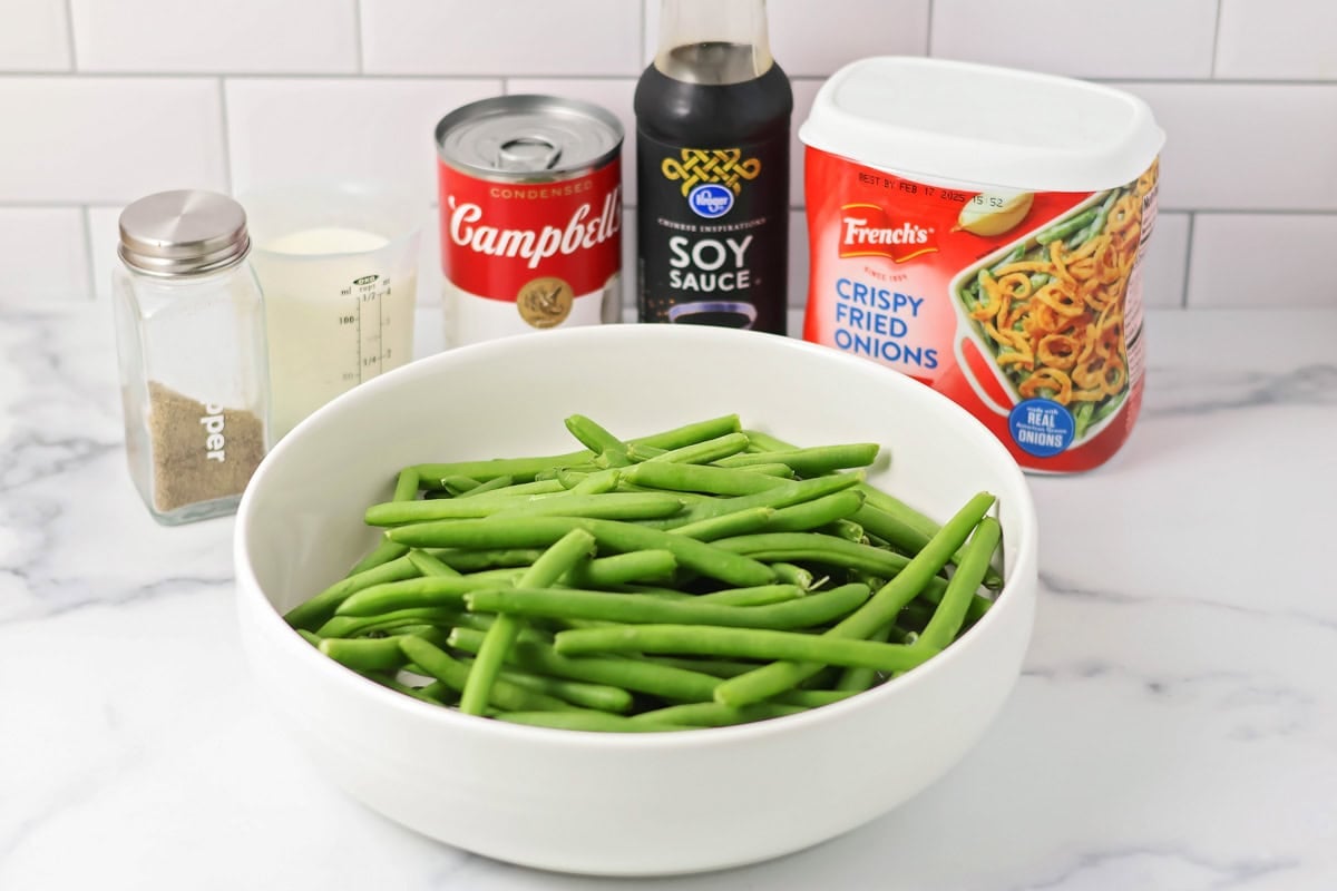 Ingredients for fresh green bean casserole on a marble countertop.