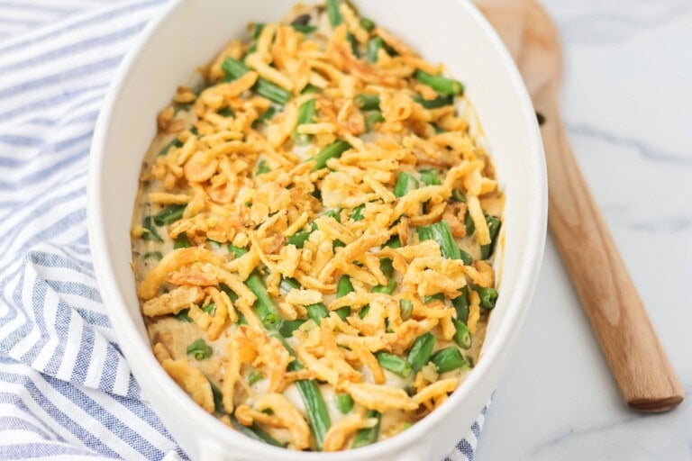 Fresh green bean casserole recipe in white baking dish with spoon.