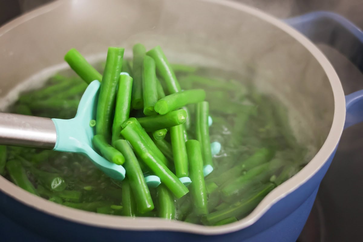 Blanching green beans in a blue pot.