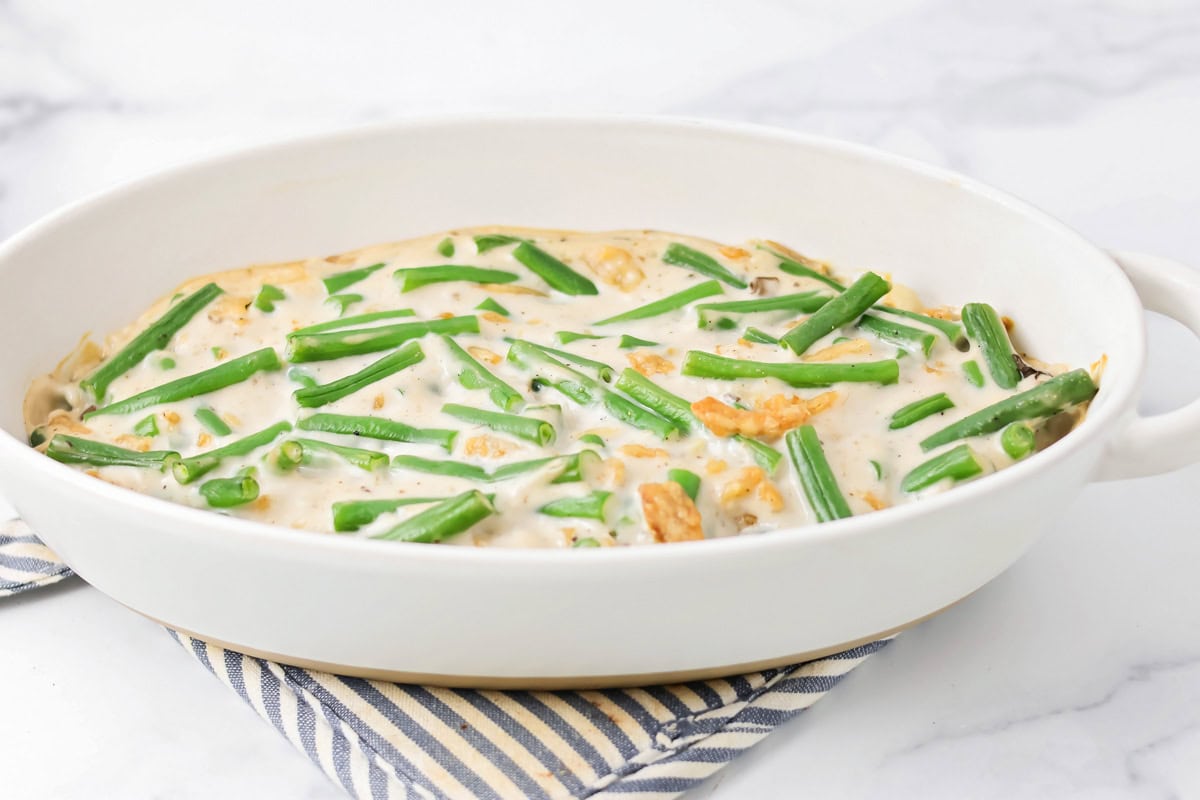 Green bean casserole mixture added to a white casserole dish.