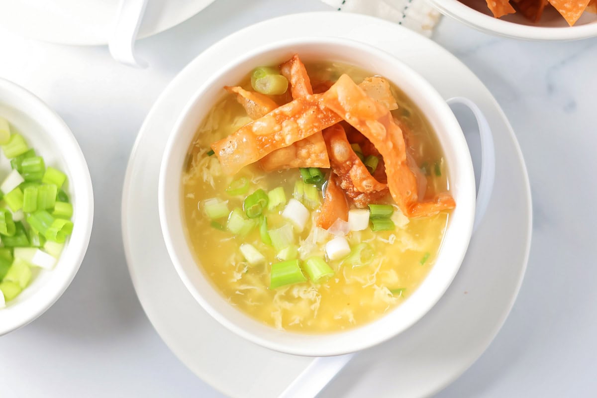 Fried wonton strips on a bowl of egg drop soup.