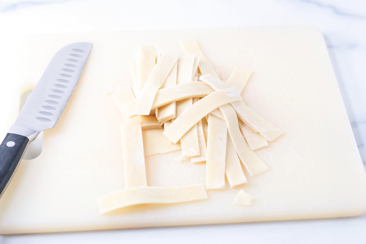 Cutting egg roll wrappers on a cutting board.