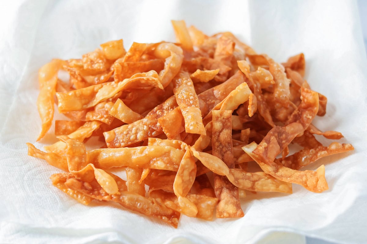 Fried wonton strips in a pile on a paper towel.