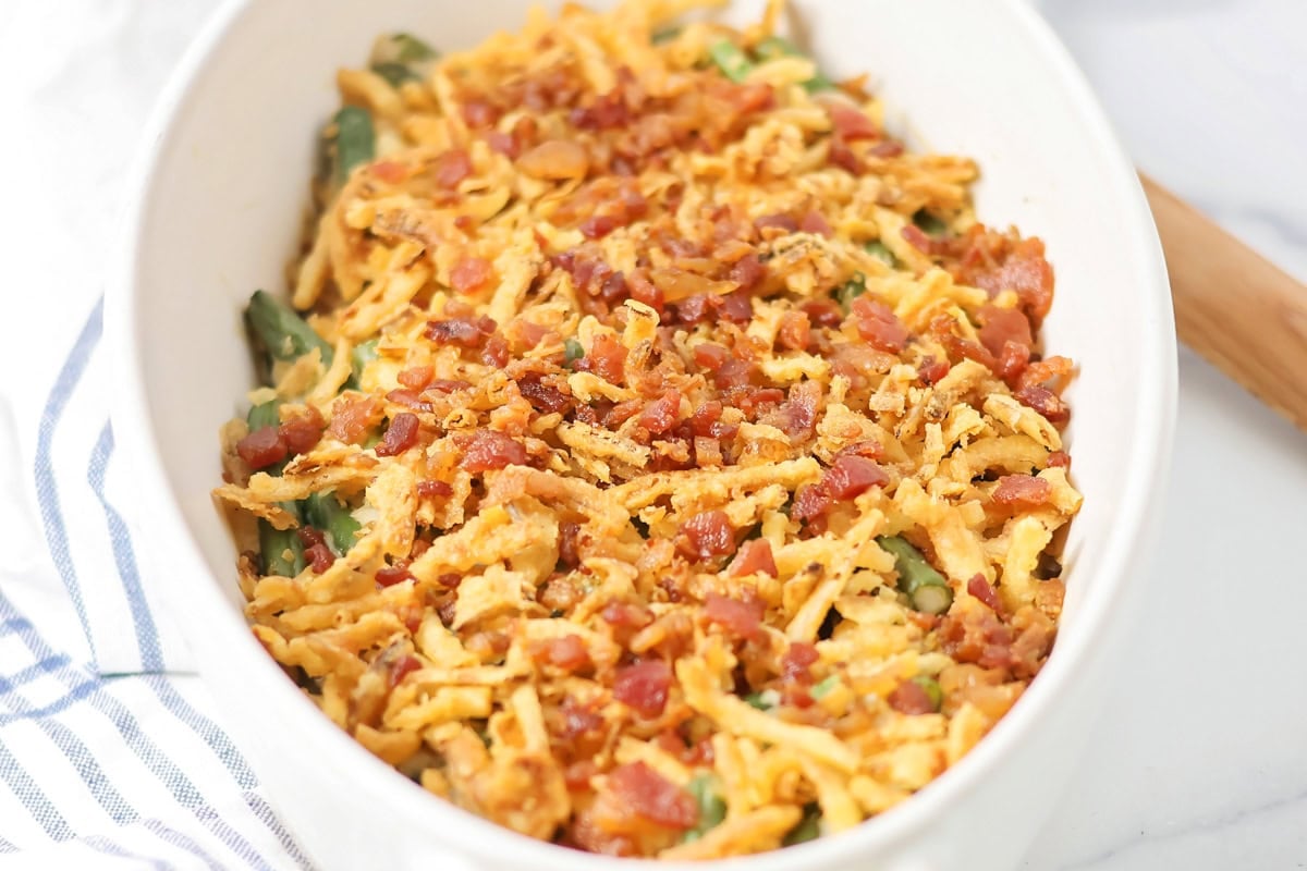 Green bean casserole with bacon in a white baking dish.