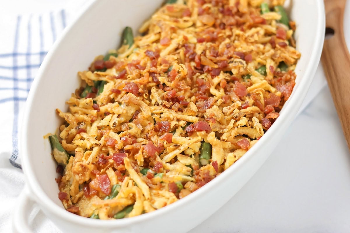 Green bean casserole with bacon in a white dish.