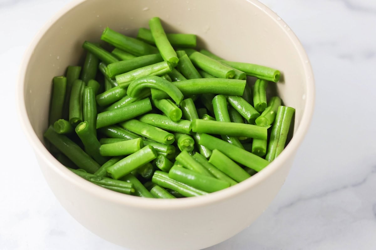 Cooked green beans in a white bowl.