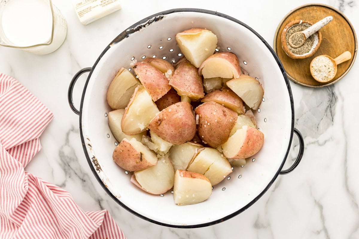 Boiled red potatoes draining in a colander.