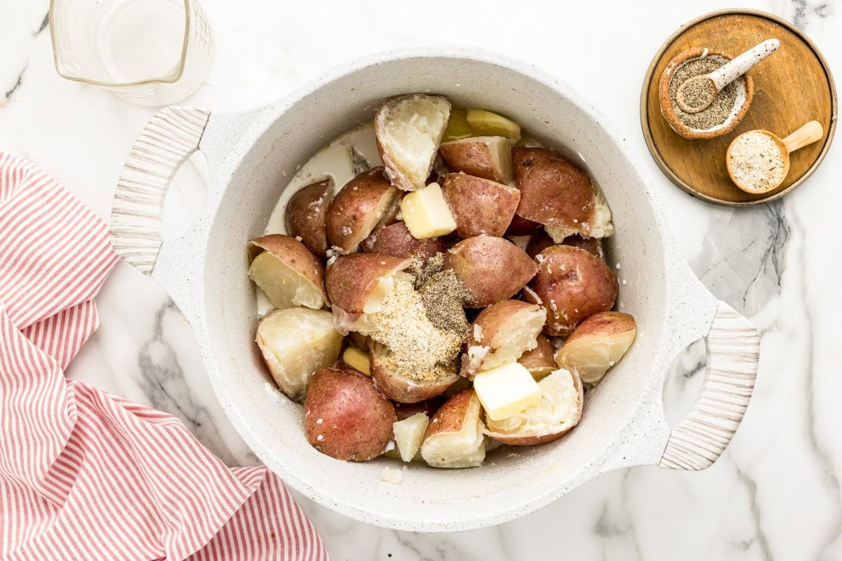 Adding ingredients to boiled potatoes to make mashed potatoes.