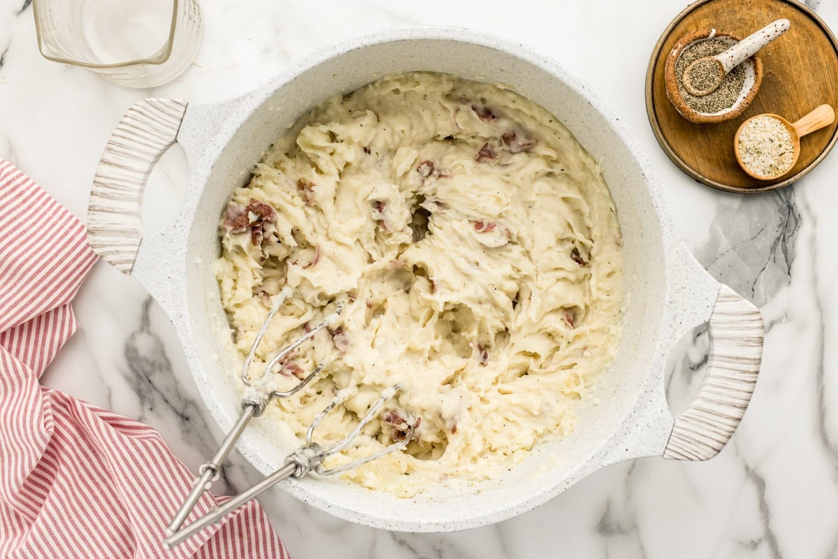 Blending mashed potatoes in a white bowl.