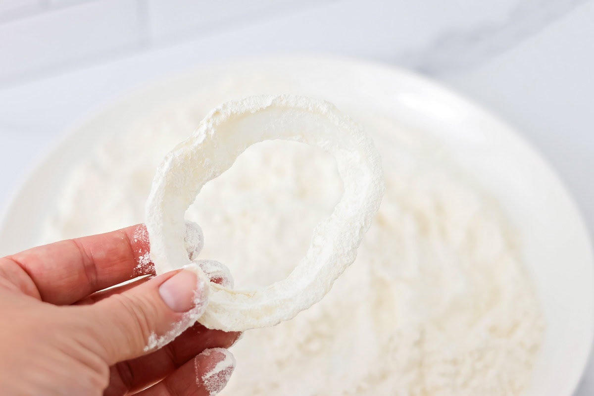 Dipping a sliced onion in flour.