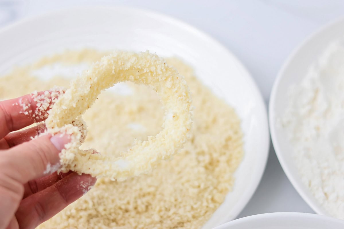 Dipping sliced onion in breadcrumbs.