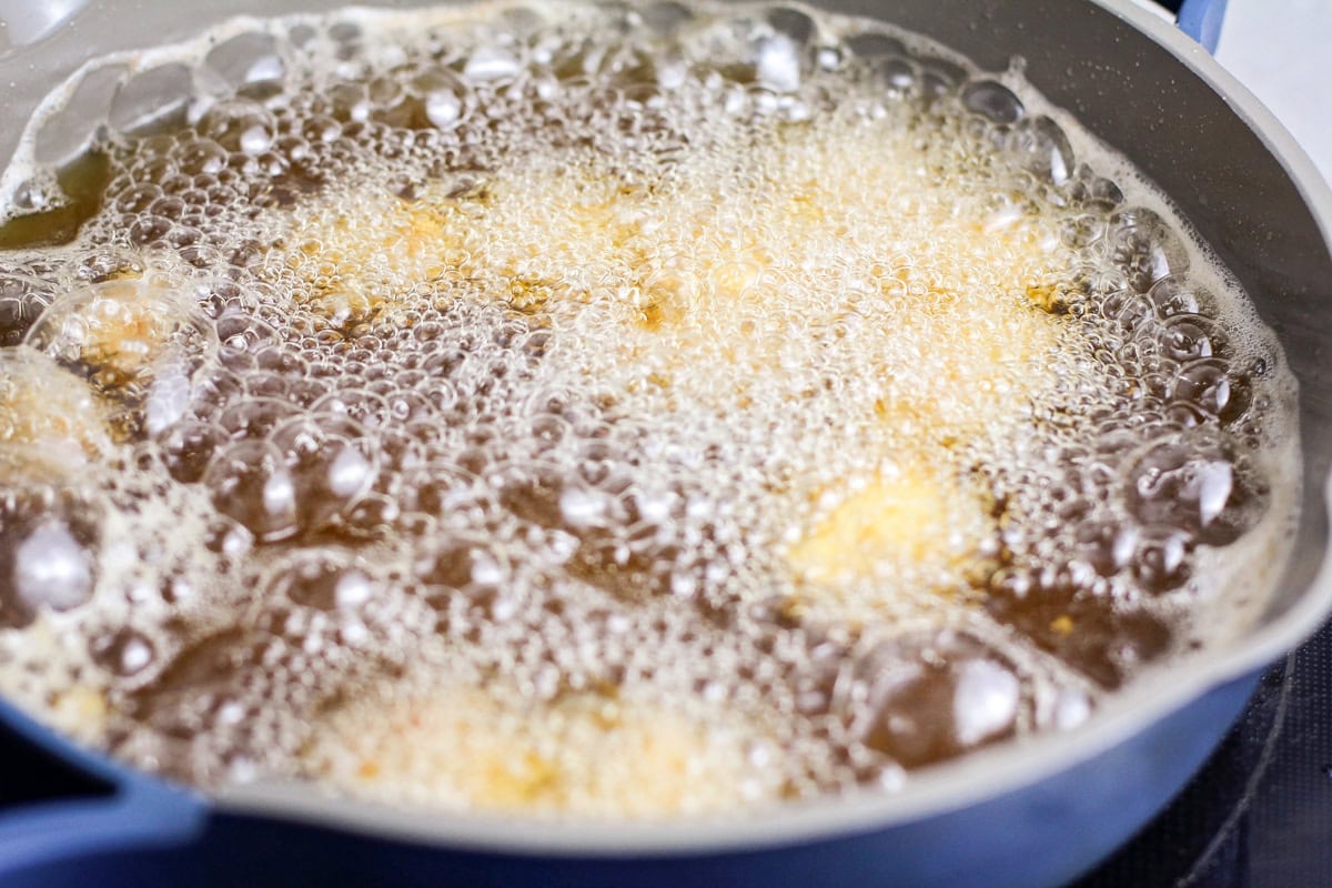 Breaded chicken pieces frying in oil.