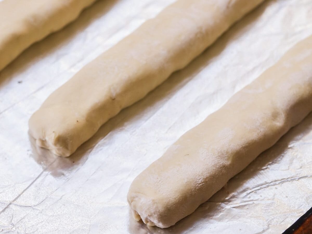 Pinching the puff pastry closed around the sausage.