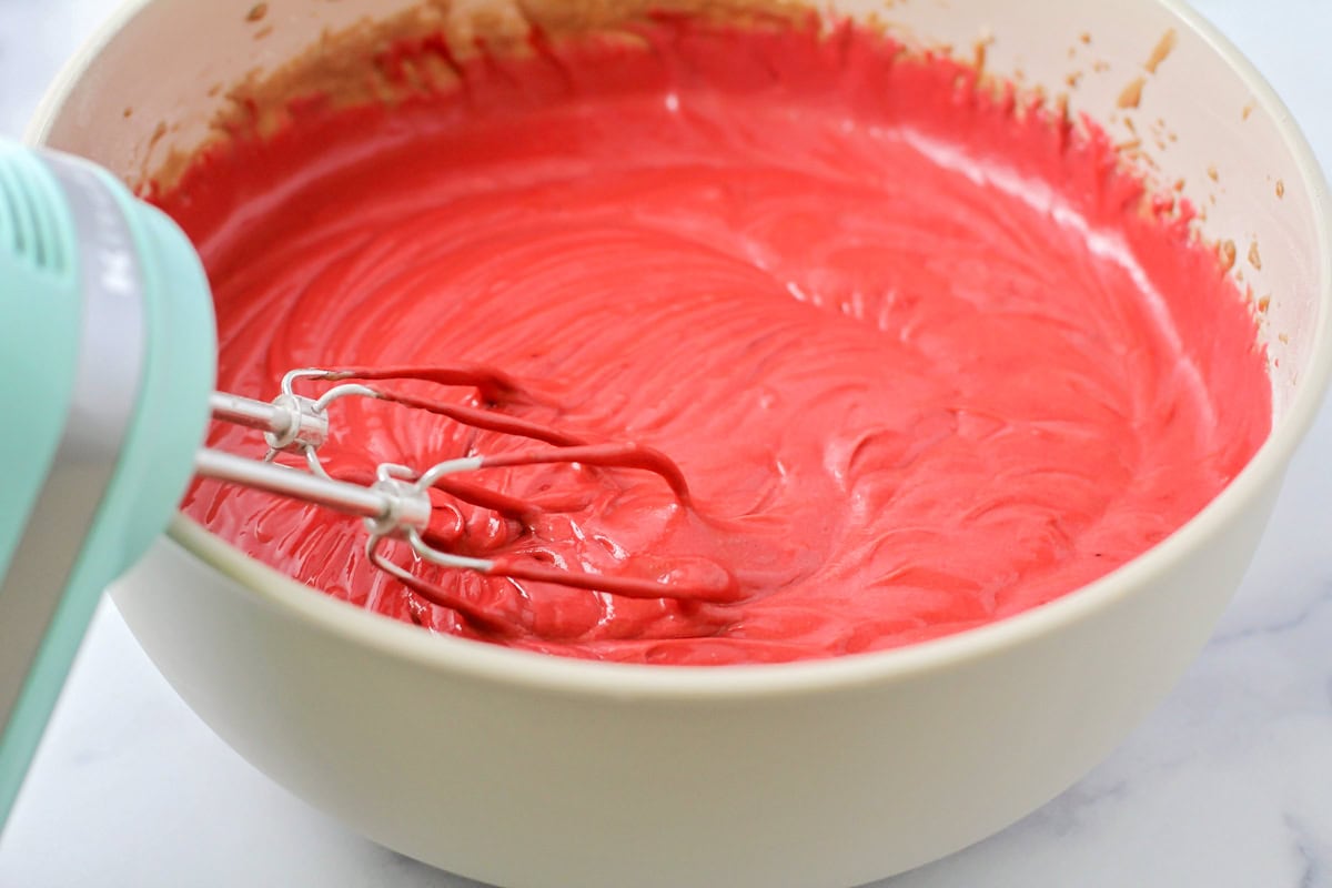 Red cake batter in a mixing bowl.