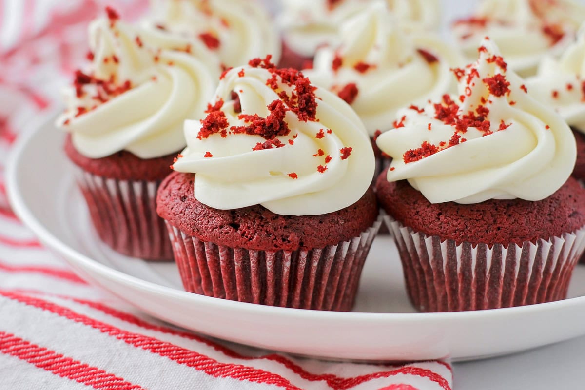 Close up several red velvet cupcakes on a white plate.