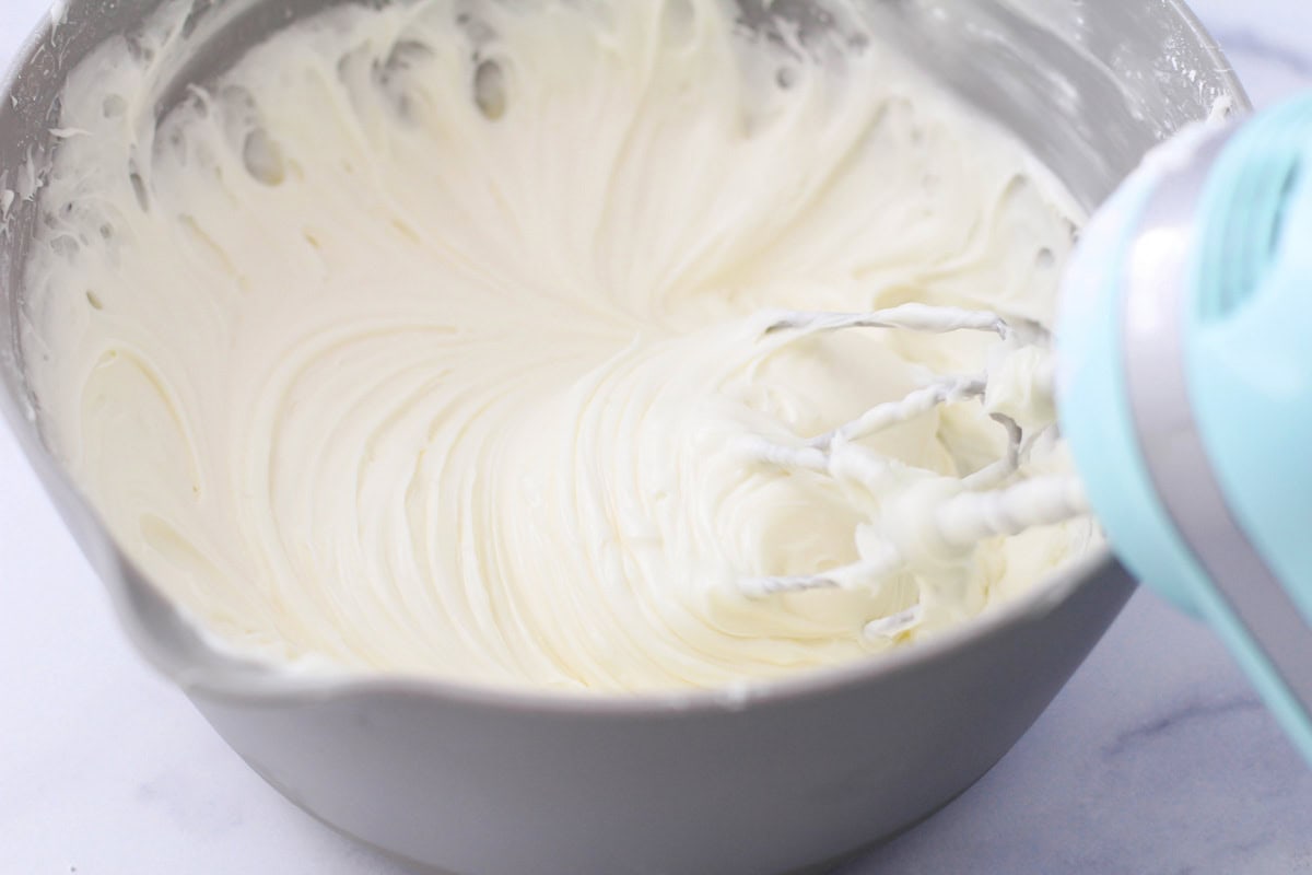 Whipping cream cheese frosting in a gray bowl.