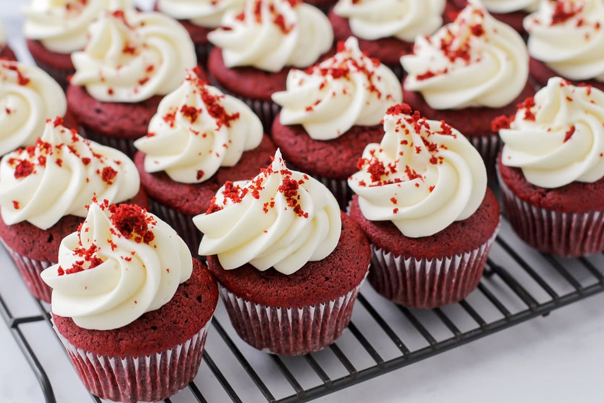 Several frosted cupcakes on a wire cooling rack.