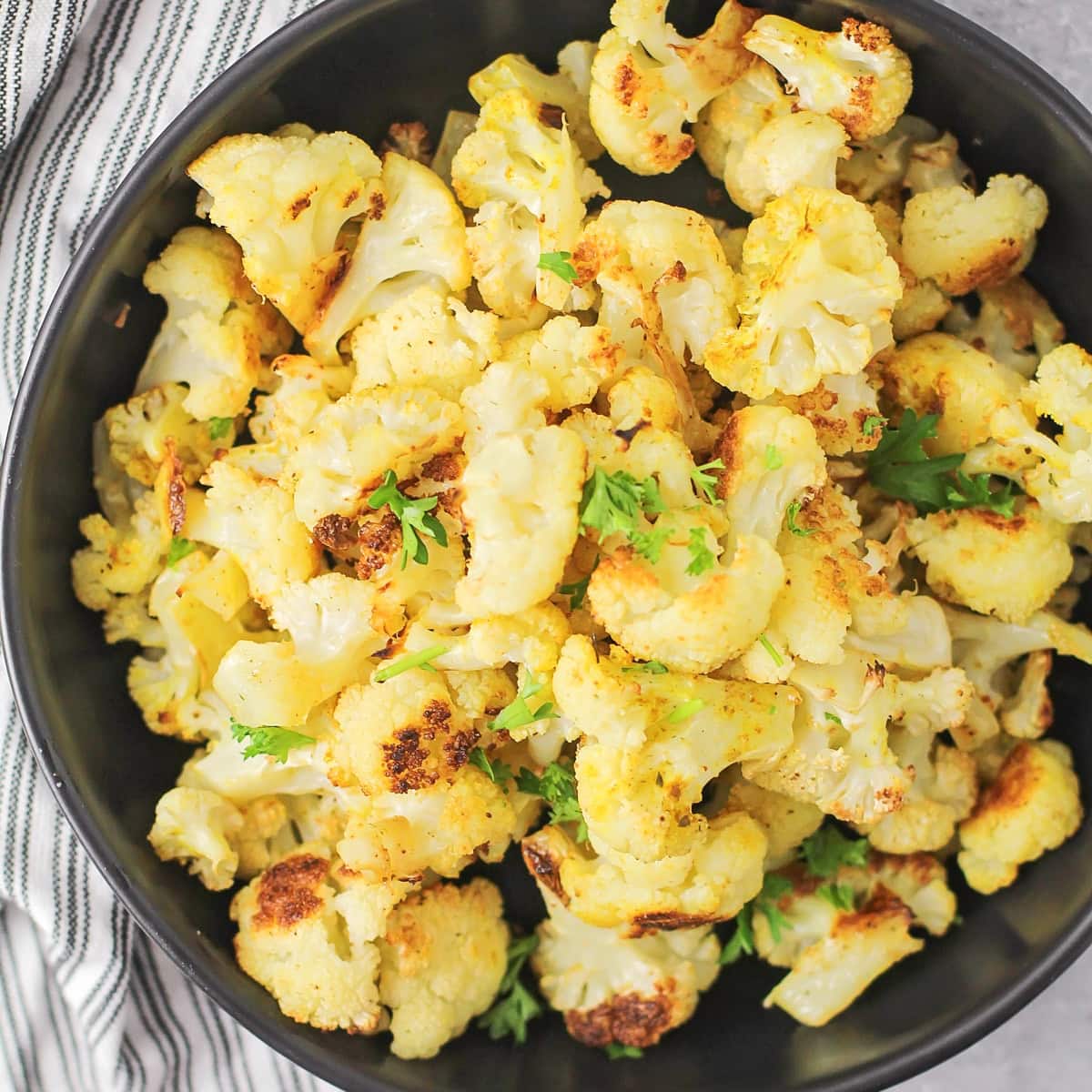 A pan of roasted cauliflower topped with fresh herbs.