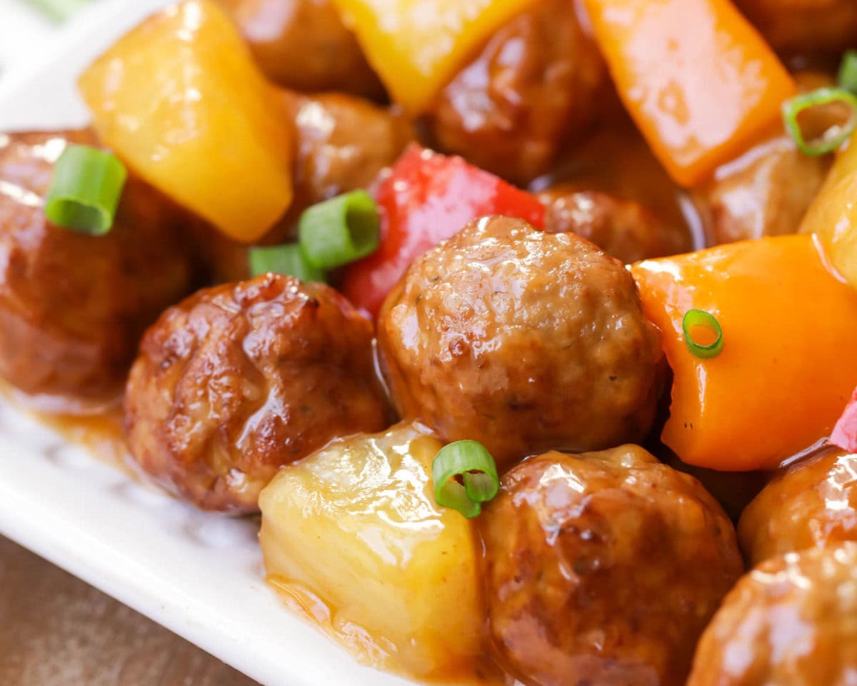 Close up image of sweet and sour meatballs with green onions on top.