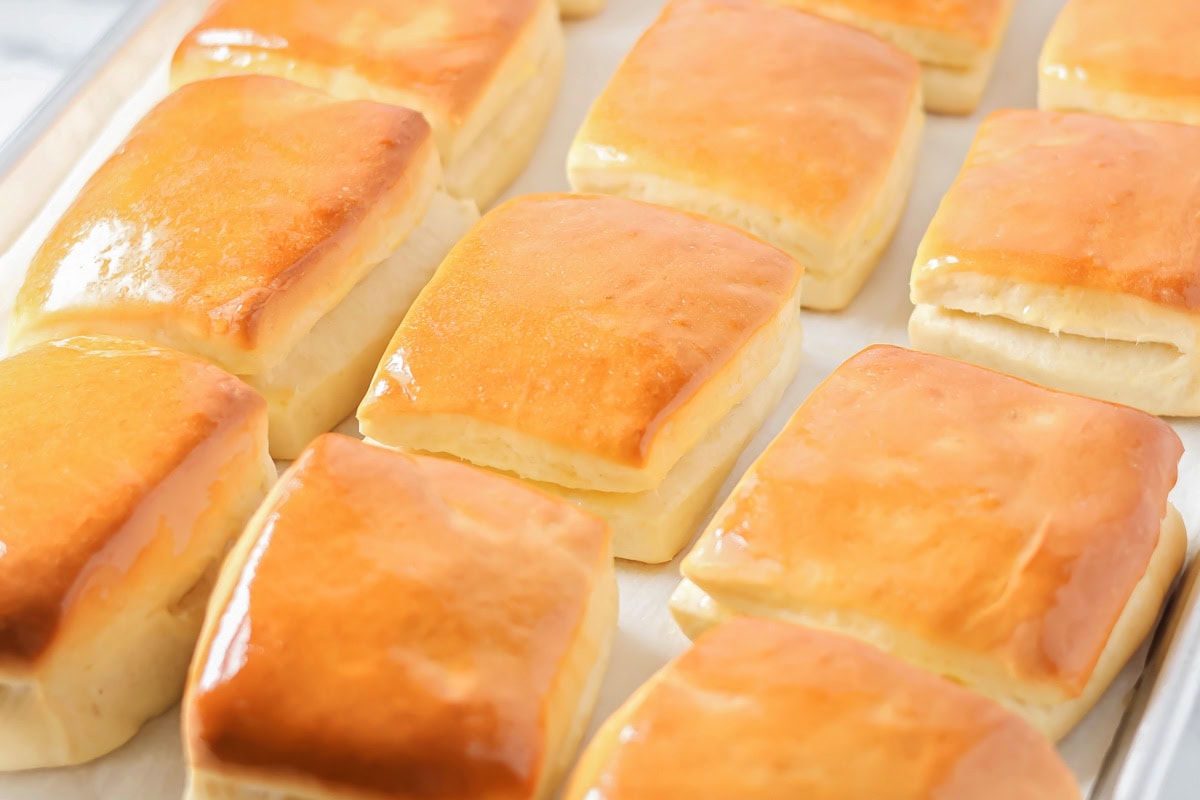 Copycat Texas Roadhouse Rolls buttered and on a baking sheet.