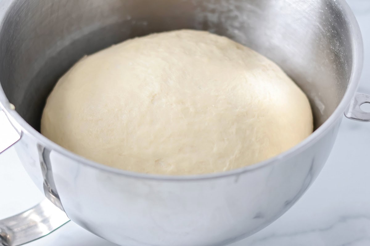 Dough ball rising in a large mixing bowl.