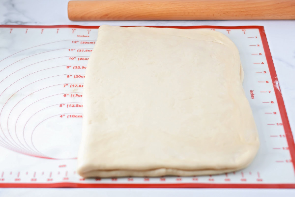 Dough for rolls folded in half on a silpat mat.