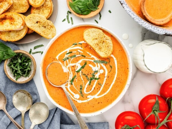 Homemade tomato bisque served in bowl and topped with sour cream and a piece of bread.