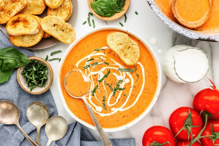 Homemade tomato bisque served in bowl and topped with sour cream and a piece of bread.