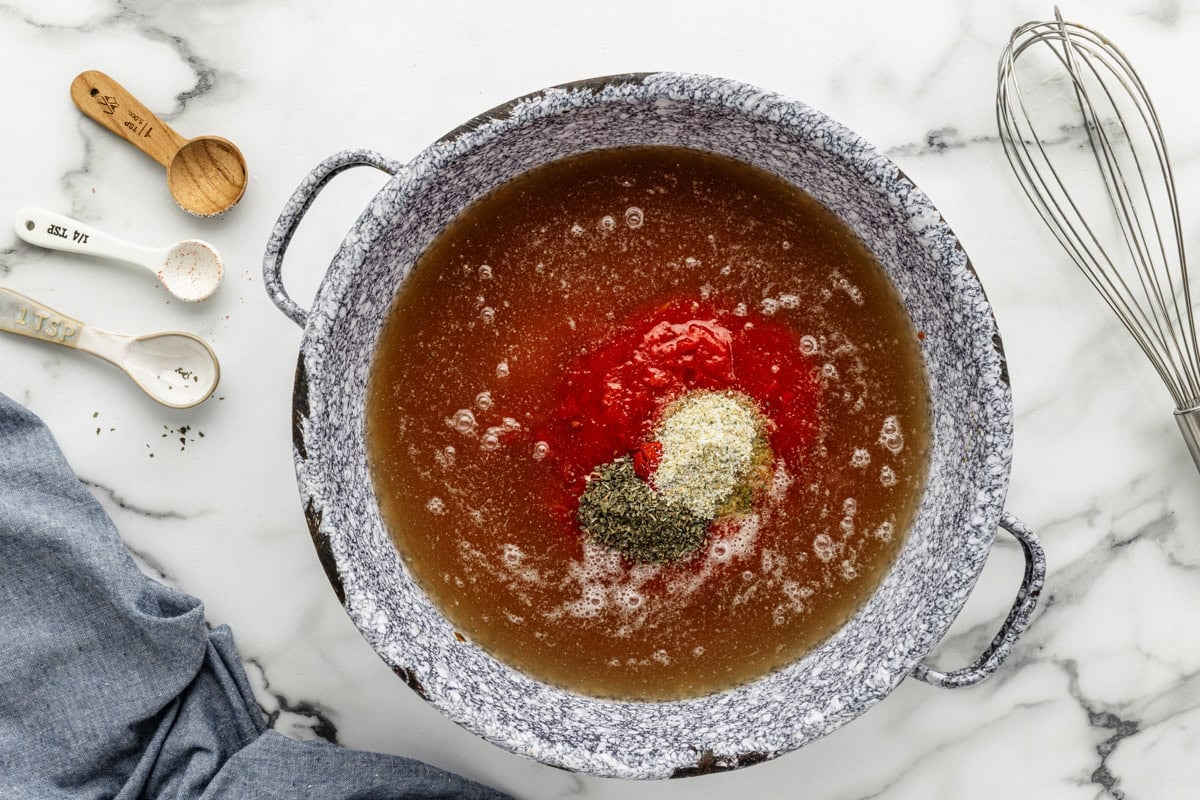 Thick, creamy, and delicious tomato bisque is a family favorite. This homemade classic is on the table in only 20 minutes! Broth, crushed tomatoes, and seasonings in a pot to make tomato bisque recipe.