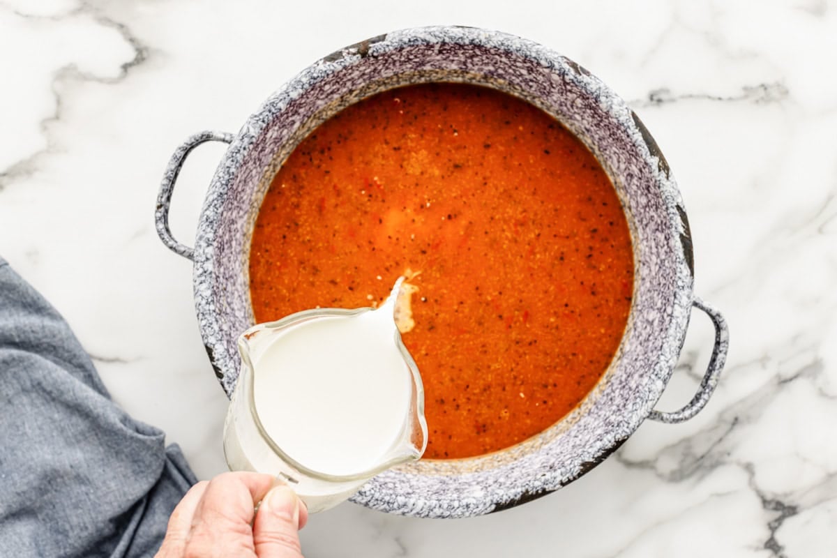 Thick, creamy, and delicious tomato bisque is a family favorite. This homemade classic is on the table in only 20 minutes! Adding half and half to a pot of blended soup.