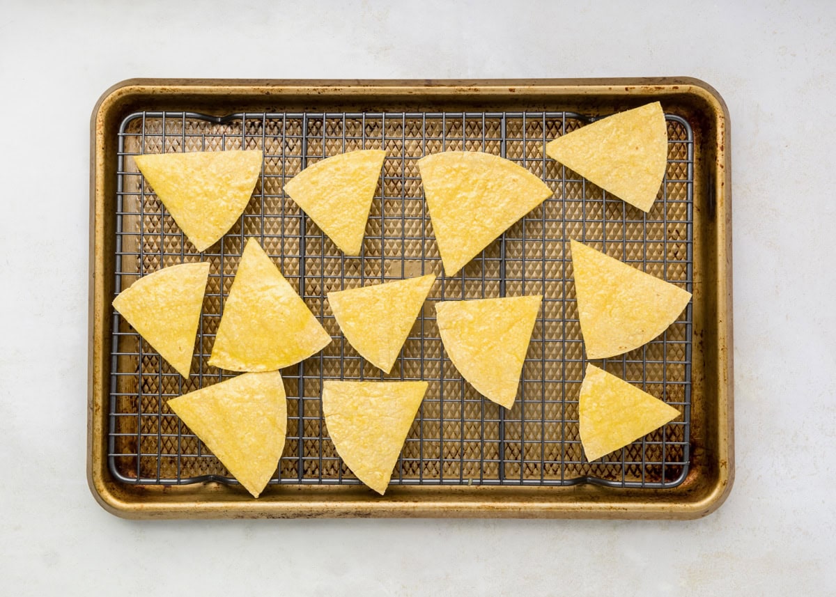 Corn tortilla triangles on a a wire rack on a baking sheet.