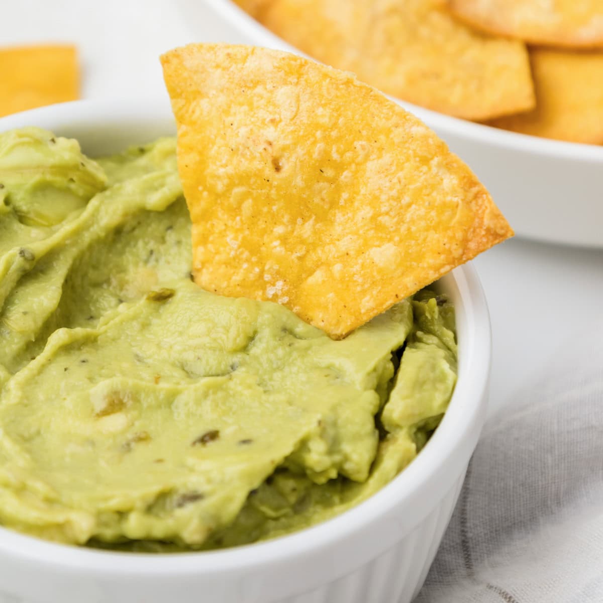 Baked tortilla chips dipped into guacamole.