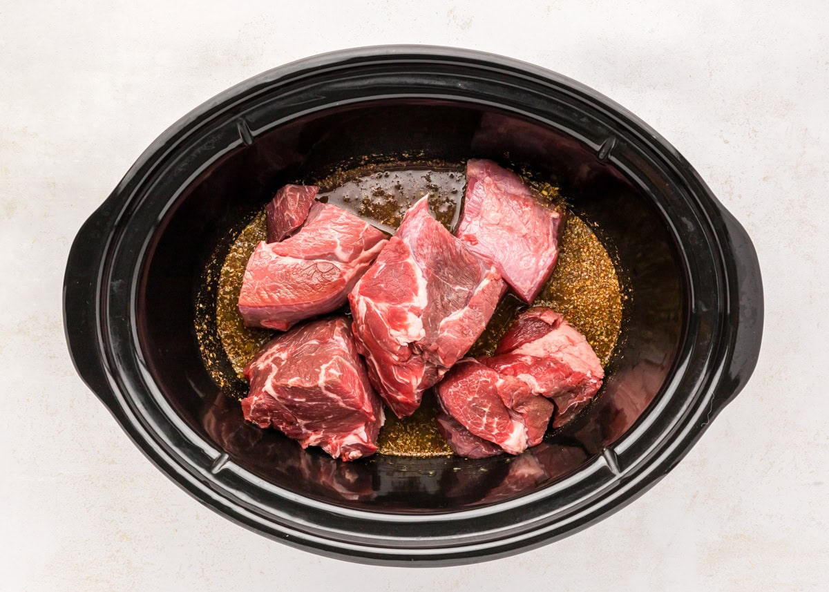 Seasonings and beef in a slow cooker.