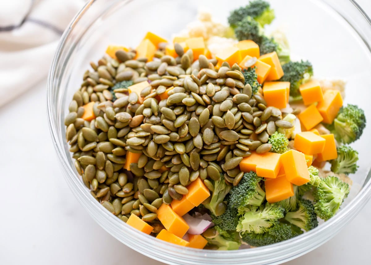 Ingredients for broccoli cauliflower salad in glass bowl.