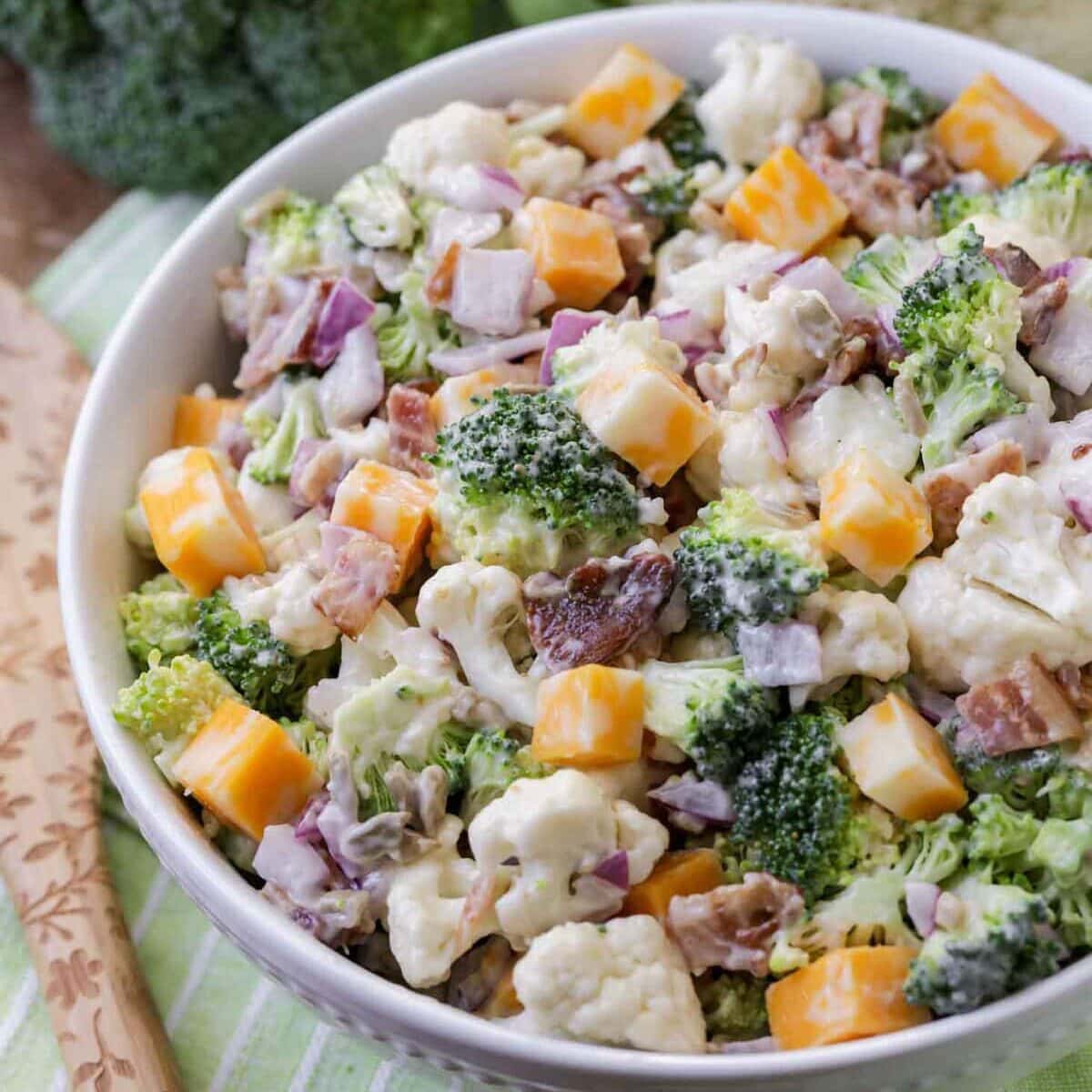 Close up image of broccoli cauliflower salad recipe in white bowl.